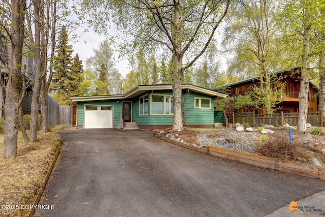 view of front of home featuring an attached garage, asphalt driveway, and fence
