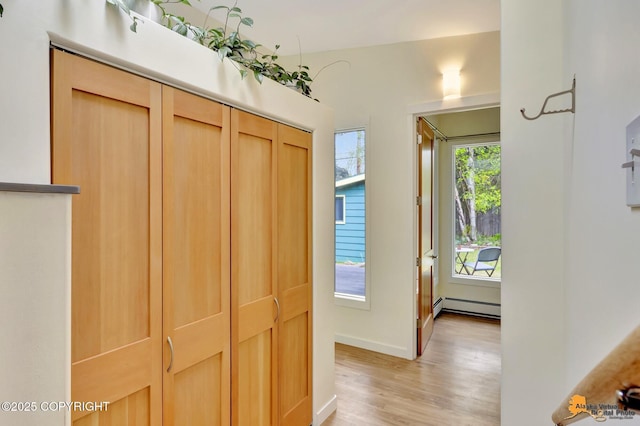 entryway featuring a baseboard radiator, light wood-style flooring, and baseboards