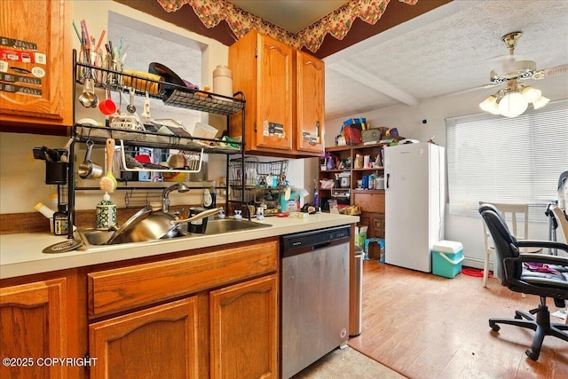 kitchen with dishwasher, freestanding refrigerator, light countertops, brown cabinets, and beam ceiling