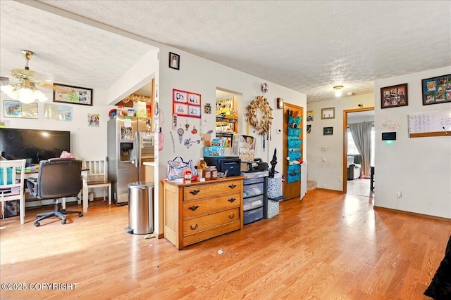 office area with a textured ceiling, light wood-style flooring, and ceiling fan