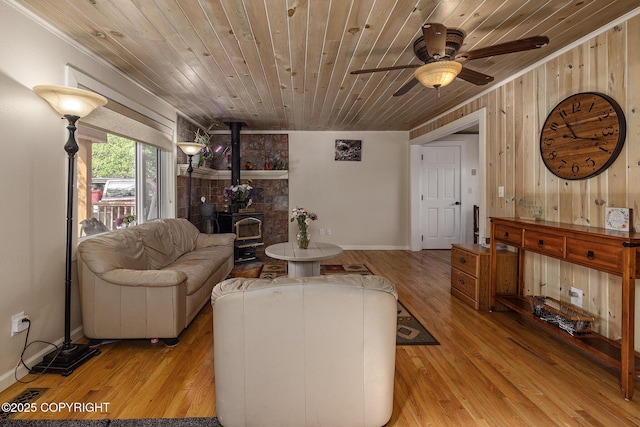 1061 E Agate Ln, Wasilla, AK 99654 - living area featuring a wood stove, wood ceiling, ceiling fan, light wood-style floors, and wood walls