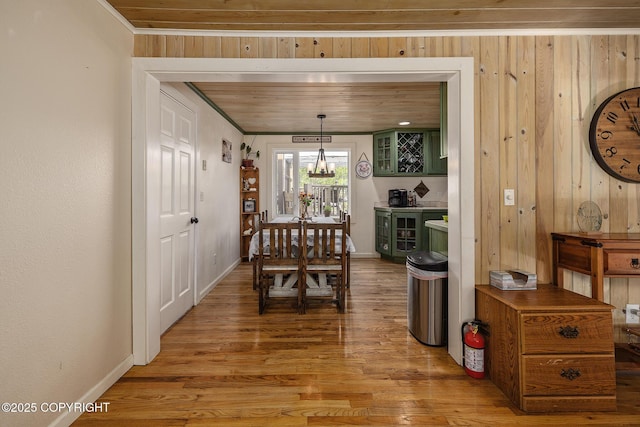 1061 E Agate Ln, Wasilla, AK 99654 - dining space featuring light wood-style floors, wood walls, baseboards, a chandelier, and crown molding