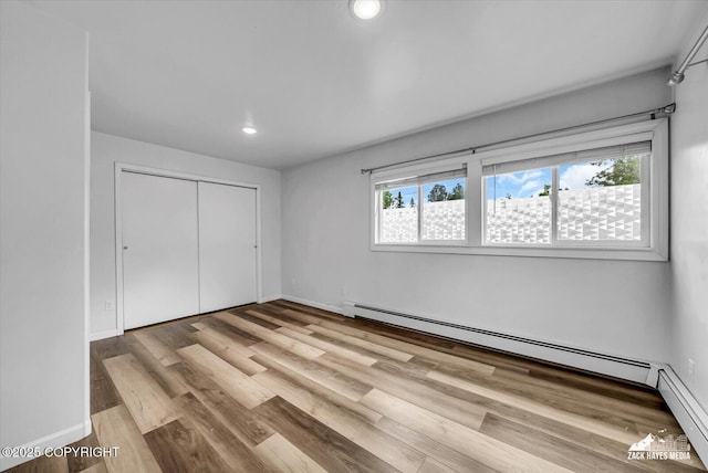 4313 Lois Dr, Anchorage, AK 99517 - unfurnished bedroom featuring wood finished floors, recessed lighting, a closet, baseboards, and a baseboard radiator