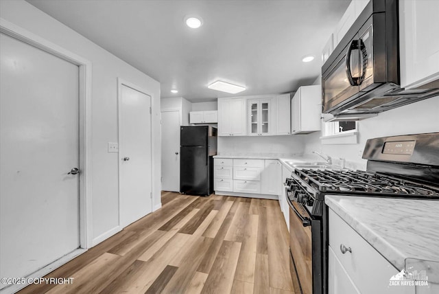 4313 Lois Dr, Anchorage, AK 99517 - kitchen with black appliances, a sink, light wood-style flooring, white cabinetry, and glass insert cabinets