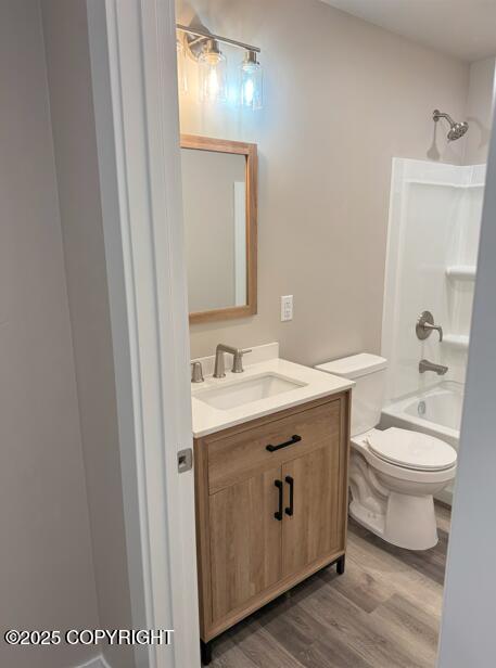 full bath featuring wood finished floors, vanity, toilet, and bathtub / shower combination