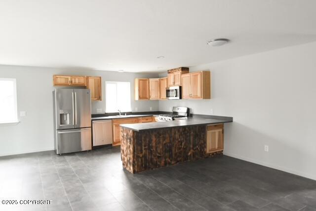 41485 Derks Lake Rd, Soldotna, AK 99669 - kitchen with stainless steel appliances, a peninsula, dark countertops, a sink, and baseboards