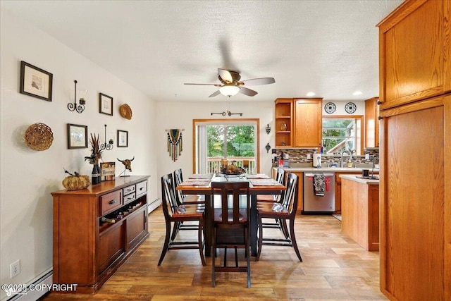 664 E Auklet Ave, Palmer, AK 99645 - dining room featuring a baseboard heating unit, ceiling fan, healthy amount of natural light, light wood-type flooring, and a textured ceiling