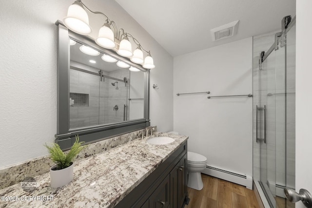 9224 Geese Cir, Eagle River, AK 99577 - bathroom with baseboard heating, a stall shower, toilet, vanity, and wood finished floors