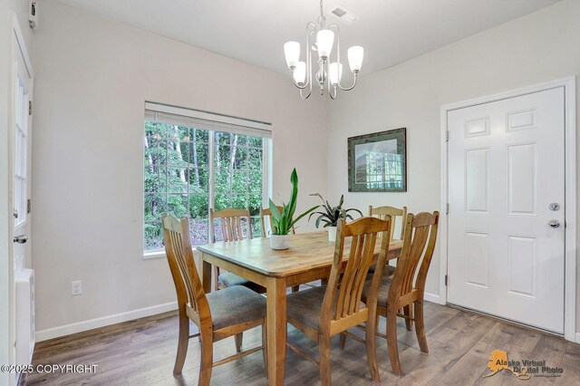 7445 W Fraki St, Wasilla, AK 99623 - dining space featuring a chandelier, wood finished floors, and baseboards