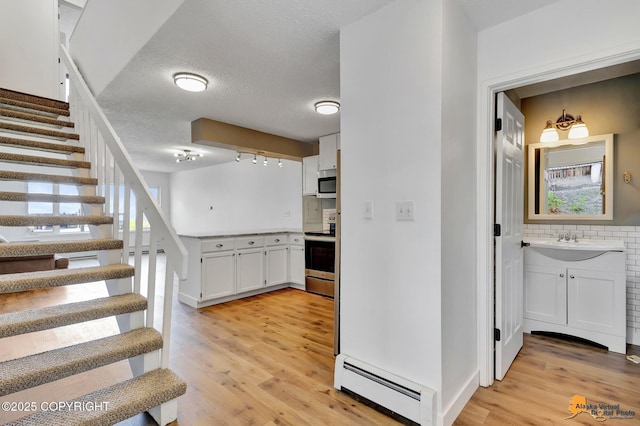 832 O Pl Unit 832, Anchorage, AK 99501 - stairs with a baseboard heating unit, healthy amount of natural light, wood finished floors, and a textured ceiling