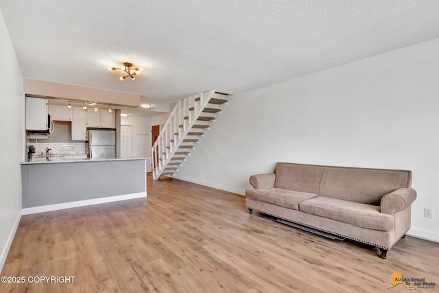 832 O Pl Unit 832, Anchorage, AK 99501 - living room with stairway, light wood finished floors, a textured ceiling, and baseboards