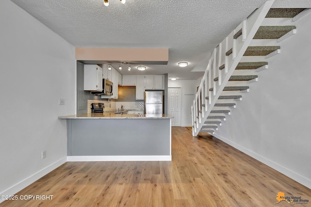 832 O Pl Unit 832, Anchorage, AK 99501 - kitchen featuring stainless steel appliances, backsplash, a peninsula, baseboards, and light wood finished floors