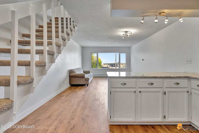 832 O Pl Unit 832, Anchorage, AK 99501 - kitchen with open floor plan, white cabinets, light wood-style flooring, a textured ceiling, and light stone countertops