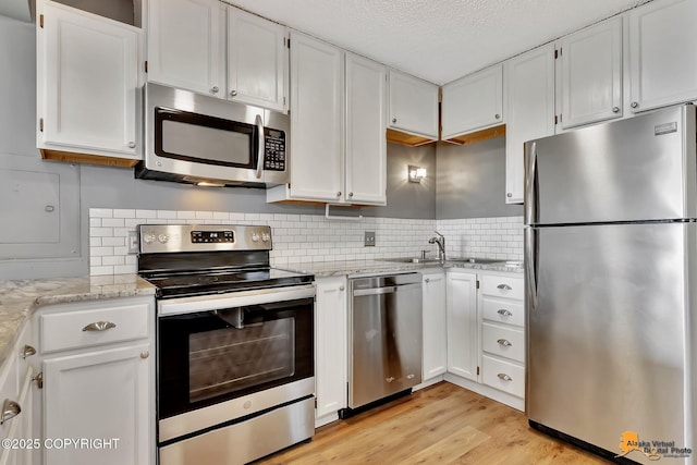 832 O Pl Unit 832, Anchorage, AK 99501 - kitchen featuring stainless steel appliances, white cabinetry, light wood-style flooring, light stone countertops, and a textured ceiling