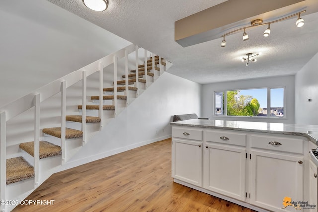 832 O Pl Unit 832, Anchorage, AK 99501 - kitchen featuring a textured ceiling, light wood finished floors, white cabinetry, and light stone counters