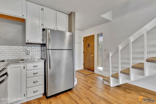 832 O Pl Unit 832, Anchorage, AK 99501 - kitchen with stainless steel appliances, light wood finished floors, white cabinets, backsplash, and a textured ceiling
