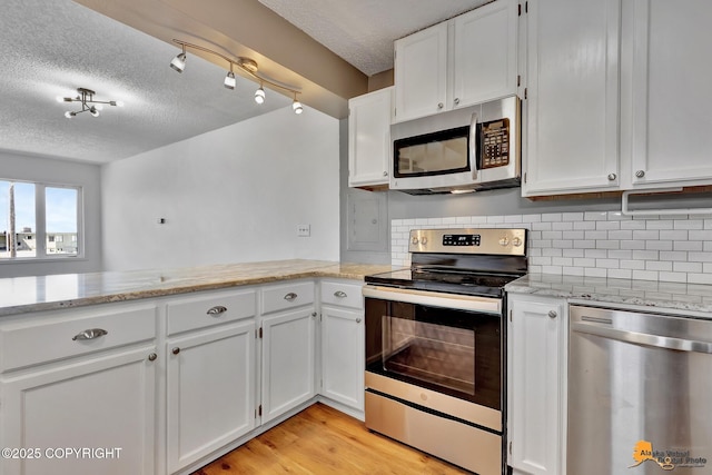 832 O Pl Unit 832, Anchorage, AK 99501 - kitchen with appliances with stainless steel finishes, a textured ceiling, white cabinets, tasteful backsplash, and light stone countertops