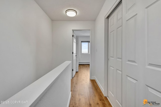 832 O Pl Unit 832, Anchorage, AK 99501 - hall featuring light wood-style flooring, baseboard heating, baseboards, and a textured ceiling