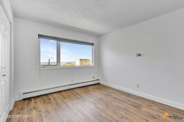 832 O Pl Unit 832, Anchorage, AK 99501 - unfurnished bedroom featuring a baseboard heating unit, a textured ceiling, wood finished floors, a closet, and baseboards