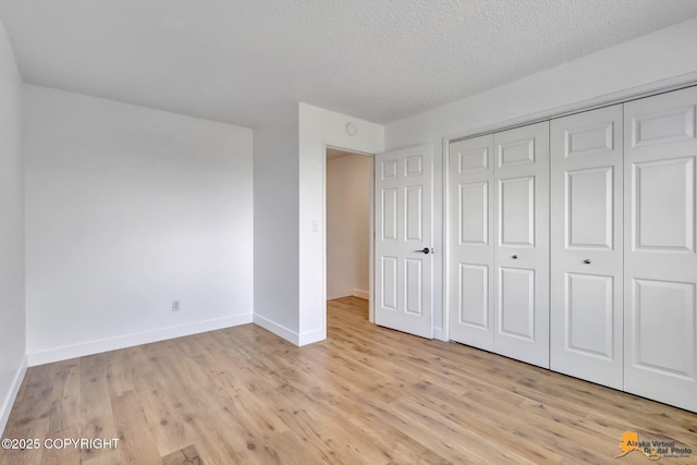 832 O Pl Unit 832, Anchorage, AK 99501 - unfurnished bedroom featuring light wood-style flooring, baseboards, a textured ceiling, and a closet