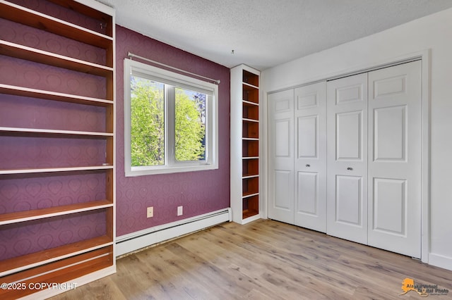 832 O Pl Unit 832, Anchorage, AK 99501 - unfurnished bedroom with baseboard heating, a textured ceiling, wood finished floors, a closet, and wallpapered walls