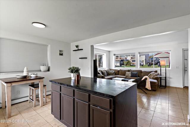 437 E 14th Ave, Anchorage, AK 99501 - kitchen featuring dark countertops, light tile patterned flooring, dark brown cabinetry, a kitchen island, and open floor plan