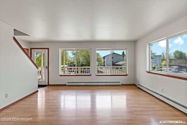 437 E 14th Ave, Anchorage, AK 99501 - unfurnished living room featuring a baseboard radiator, a baseboard heating unit, light wood-type flooring, and baseboards