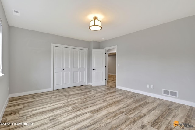 6033 Heather Wood Cir, Anchorage, AK 99502 - unfurnished bedroom with baseboards, a closet, and light wood-type flooring