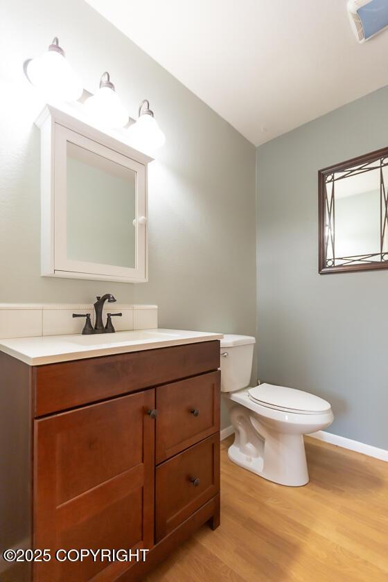 19404 Middleton Loop, Eagle River, AK 99577 - bathroom featuring baseboards, wood finished floors, toilet, and vanity