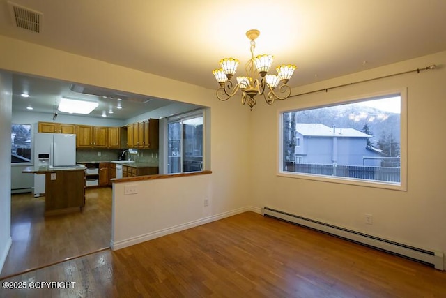 19404 Middleton Loop, Eagle River, AK 99577 - kitchen featuring a baseboard heating unit, a chandelier, wood finished floors, brown cabinets, and healthy amount of natural light