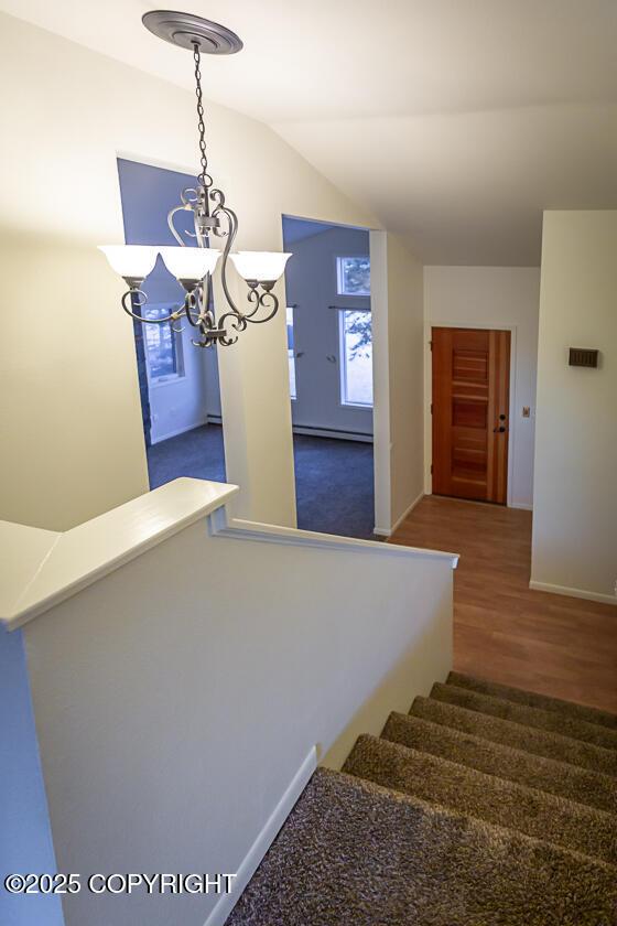 19404 Middleton Loop, Eagle River, AK 99577 - stairway featuring a chandelier, wood finished floors, a baseboard radiator, baseboards, and lofted ceiling