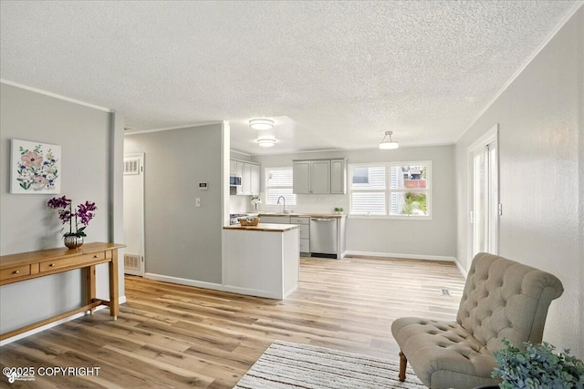 3624 E 16th Ave, Anchorage, AK 99508 - living area with light wood-style floors, a textured ceiling, baseboards, and crown molding