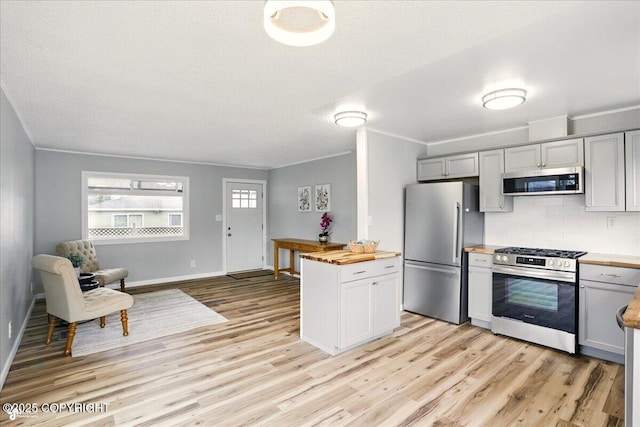 3624 E 16th Ave, Anchorage, AK 99508 - kitchen with appliances with stainless steel finishes, wooden counters, light wood-type flooring, decorative backsplash, and ornamental molding