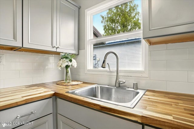 3624 E 16th Ave, Anchorage, AK 99508 - kitchen featuring butcher block counters, a sink, decorative backsplash, and gray cabinetry