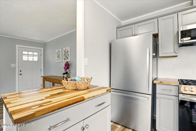 3624 E 16th Ave, Anchorage, AK 99508 - kitchen featuring butcher block countertops, stainless steel appliances, gray cabinets, decorative backsplash, and a textured ceiling