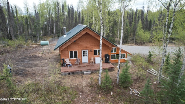 back of property featuring a wooded view and a deck