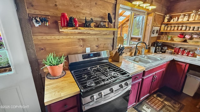 kitchen featuring stainless steel gas stove, a sink, healthy amount of natural light, and dark brown cabinets