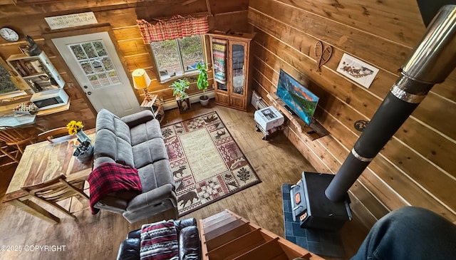 living room featuring a wood stove, hardwood / wood-style floors, and wood walls