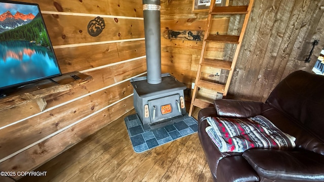 living area with a wood stove, wood-type flooring, and wood walls
