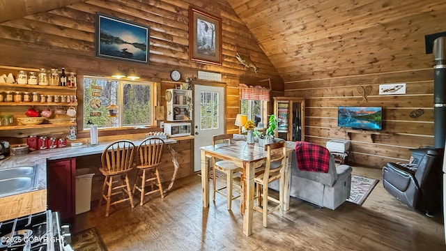 dining area featuring a wood stove, vaulted ceiling, plenty of natural light, wooden walls, and wooden ceiling