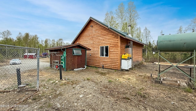 view of property exterior featuring log veneer siding, fence, an outdoor structure, and a storage unit