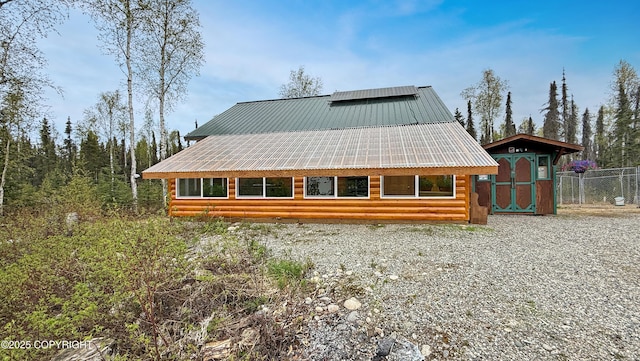 back of property featuring metal roof, a storage unit, an outbuilding, and fence