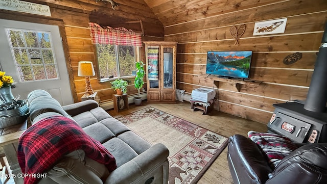 living area with vaulted ceiling, wooden walls, a wood stove, light wood-style floors, and wooden ceiling