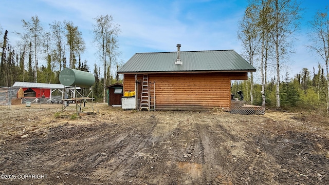 view of home's exterior featuring log veneer siding, metal roof, and an outbuilding