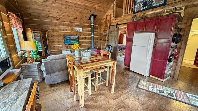 dining space with lofted ceiling, wood walls, a wood stove, wood ceiling, and hardwood / wood-style flooring
