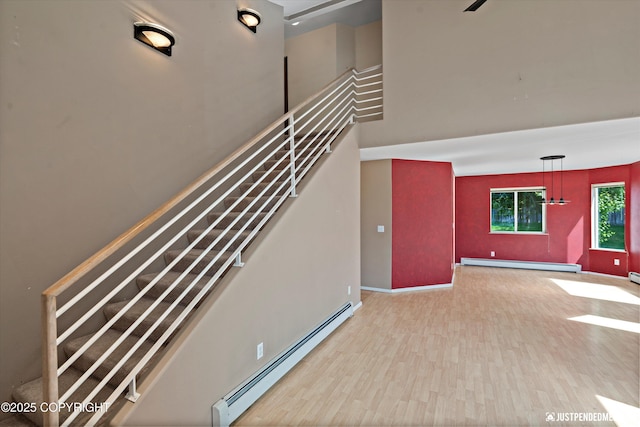 10321 Compass Cir, Anchorage, AK 99515 - stairway with a baseboard heating unit, baseboards, wood finished floors, and a high ceiling
