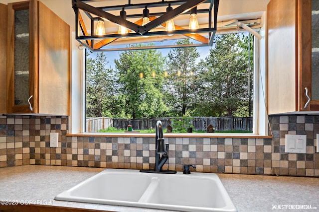 10321 Compass Cir, Anchorage, AK 99515 - kitchen view of a sink, backsplash, light countertops, glass insert cabinets, and a chandelier