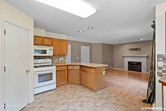 10321 Compass Cir, Anchorage, AK 99515 - kitchen featuring white appliances, a peninsula, light countertops, a baseboard radiator, and a tiled fireplace