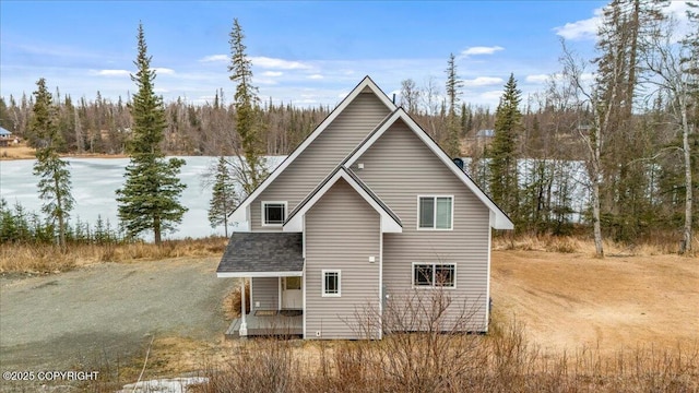 53578 Bell Ave, Nikiski/North Kenai, AK 99611 - rear view of house featuring covered porch, a shingled roof, and a forest view