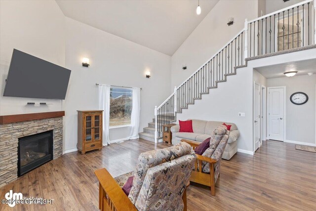 53578 Bell Ave, Nikiski/North Kenai, AK 99611 - living area featuring high vaulted ceiling, stairway, wood finished floors, baseboards, and a stone fireplace